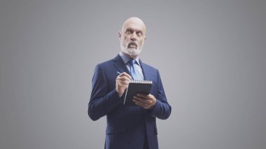 İşletme yöneticisi notlar yazıyor ve bir deftere listeler yapıyor, gri arka planda izole edilmiş.
