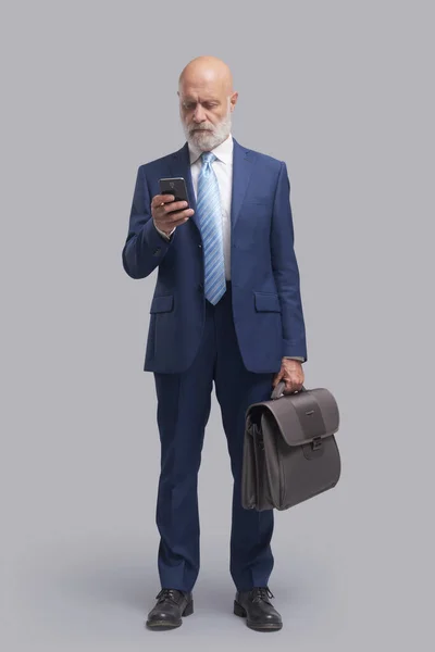 Senior Geschäftsmann Plaudert Mit Seinem Smartphone Und Hält Eine Aktentasche — Stockfoto