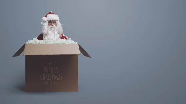 Funny confused Santa Claus inside a delivery box and Christmas wishes