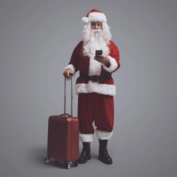 Resande Jultomten Håller Vagn Väska Och Chatta Med Sin Smartphone — Stockfoto
