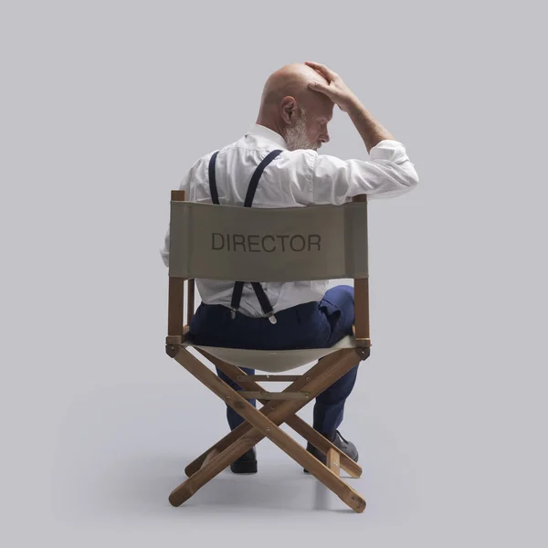 監督の椅子に座り 頭に触れるという失意のうちに 彼は強調され 絶望的な思いをする — ストック写真