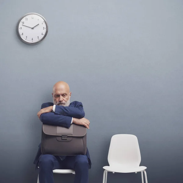 Corporate businessman sitting in the waiting room, he is waiting for a job interview, employment and recruitment concept