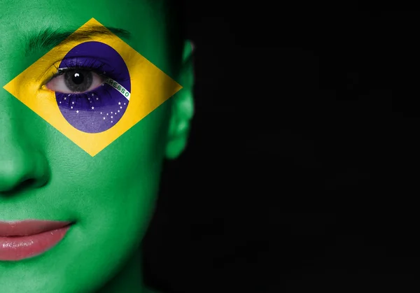 Retrato de uma mulher com a bandeira do Brasil pintada em seu rosto — Fotografia de Stock