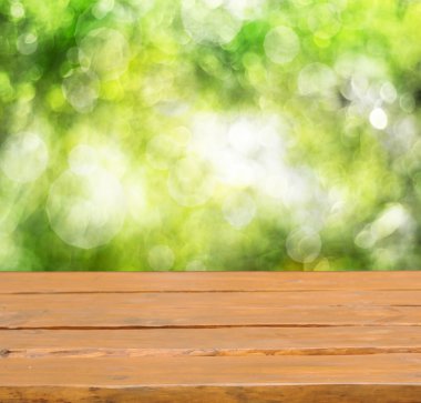 Yaprak bokeh arkaplanlı boş ahşap güverte masası.