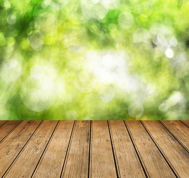 Yaprak bokeh arkaplanlı boş ahşap güverte masası.