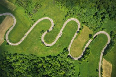 Yeşil orman arasındaki dolambaçlı yolun hava aracı görüntüsü