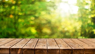 Arka planda taze yeşil baharı olan boş eski ahşap masa.