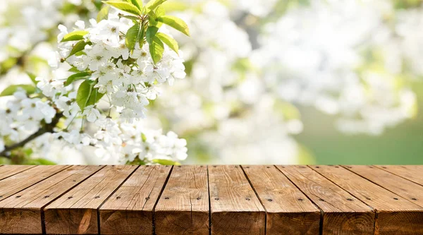 Arka planda bahar çiçekleri olan boş ahşap masa