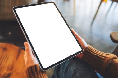 Ahşap masada beyaz ekranlı siyah tabletli bir kadının görüntüsü.