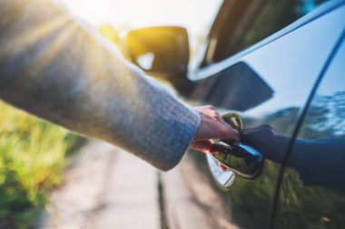 Arabanın kapısını açan bir kadının yakın plan görüntüsü.