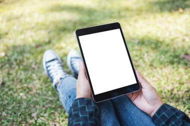 Açık havada otururken beyaz ekranlı siyah tablet tableti tutan ve kullanan bir kadının görüntüsü