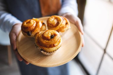 Bir garson elinde tahtadan bir tabak Danimarka üzümü tutuyor. 