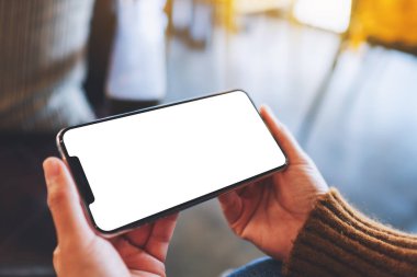 Boş masaüstü ekran ile siyah cep telefonu tutan bir kadının görüntüsü 