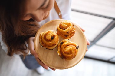 Bir garsonun elinde kuru üzümlü çöreğin ahşap tabakta kokladığı en iyi görüntü.