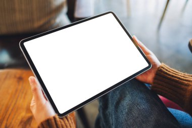 Ahşap masada beyaz ekranlı siyah tabletli bir kadının görüntüsü.