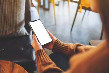 Boş masaüstü ekran ile siyah cep telefonu tutan bir kadının görüntüsü 