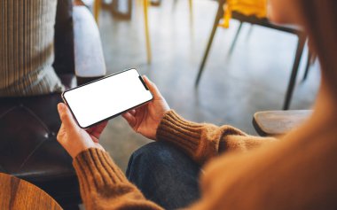 Boş masaüstü ekran ile siyah cep telefonu tutan bir kadının görüntüsü 