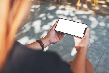 Boş masaüstü ekran ile siyah cep telefonu tutan bir kadının görüntüsü