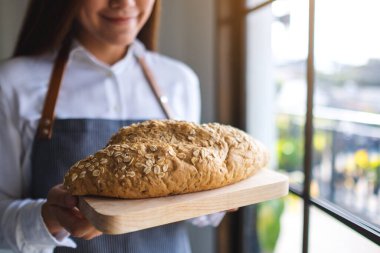 Bir somun ekmeği tutup servis eden bir garson.