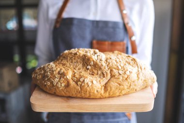 Bir somun ekmeği tutup servis eden bir garson.