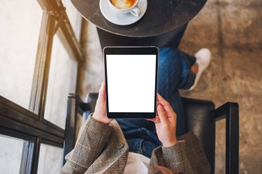 Boş beyaz masaüstü ekran ile siyah tablet bilgisayarını tutan bir kadının en üst görünüm görüntüsü 