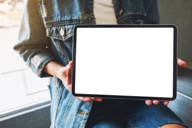 Kafedeki boş beyaz ekranlı siyah tableti tutan ve gösteren bir kadının görüntüsü