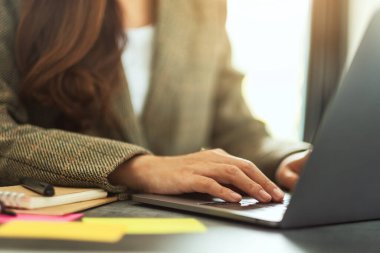 İş kadını dizüstü bilgisayarında ofis masasında kağıt işleriyle daktilo kullanıyor.