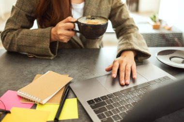 İş kadını ofiste kahve içerken bilgisayara dokunuyor ve dokunuyor.