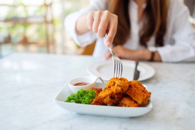 Restoranda kızarmış tavuk yiyen bir kadının yakın plan görüntüsü.