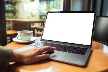 Masasında kahve fincanı olan ve boş beyaz masaüstü ekranı olan bir kadının laptopa dokunuşunu ve dokunuşunu görüntüle. 