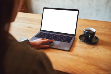 Laptop dokunmatik dokunmatik ekranlı, boş beyaz masaüstü ekranlı ve ahşap masada kahve fincanı olan bir kadının görüntüsü.