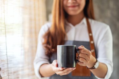 Bir garson kafede bir fincan sıcak kahve ikram ediyor.