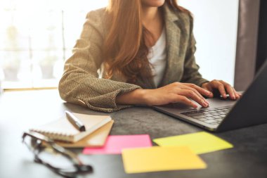 İş kadını dizüstü bilgisayarında ofis masasında kağıt işleriyle daktilo kullanıyor.