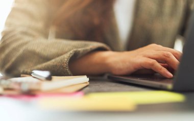 İş kadını dizüstü bilgisayarında ofis masasında kağıt işleriyle daktilo kullanıyor.