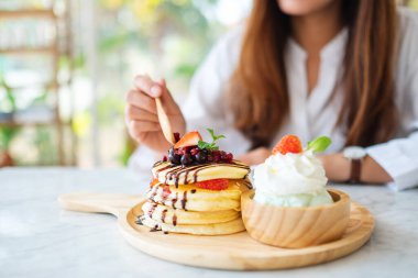 Karışık böğürtlenli krep yiyen bir kadın. Dondurma ve çırpılmış krema.