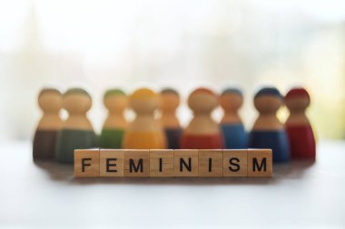 Ahşap bloklar ve arka planda bir grup kadın hakkında FemINISM kelimesi