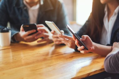 Birlikte otururken cep telefonunu kullanan ve ona bakan bir grup insan.
