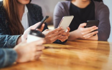 Birlikte otururken cep telefonunu kullanan ve ona bakan bir grup insan.