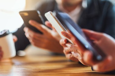 Birlikte otururken cep telefonunu kullanan ve ona bakan bir grup insan.