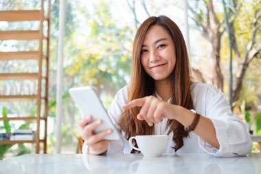 Güzel bir Asyalı kadının cep telefonunu kullanırken ve işaret ederken yakın plan görüntüsü.