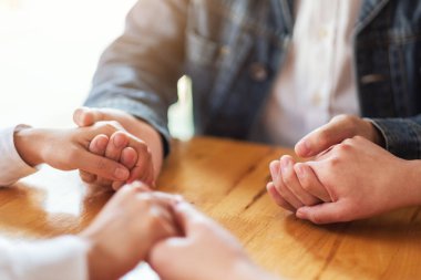 Bir grup insan el ele tutuşarak ya da terapi seansında bir araya gelip dua ediyorlar. 