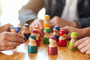 İnsanlar masadaki bir gruptan tahta figürleri seçip alıyor.