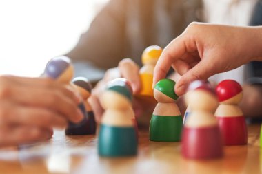 İnsanlar masadaki bir gruptan tahta figürleri seçip alıyor.