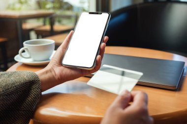 Ofiste boş masaüstü ekranı olan, kredi kartı ve cep telefonu tutan ellerin görüntüsü