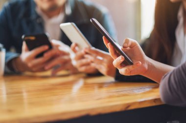 Birlikte otururken cep telefonunu kullanan ve ona bakan bir grup insan.