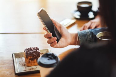 Kafede aynı cep telefonunu kullanan ve ona bakan bir grup Asyalı genç.