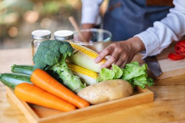 Sebze tepsisinden taze mısır toplayan bir kadın şef.