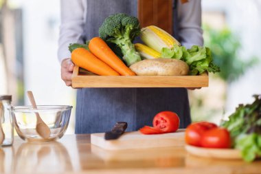 Ahşap tepside taze sebze tutan bir kadın şef.