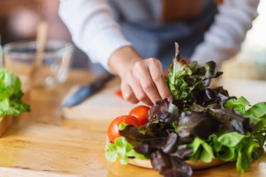 Bir kadın aşçının yakın plan görüntüsü mutfakta pişirmek için marul ve sebze hazırlayın.