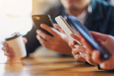 Birlikte otururken cep telefonunu kullanan ve ona bakan bir grup insan.